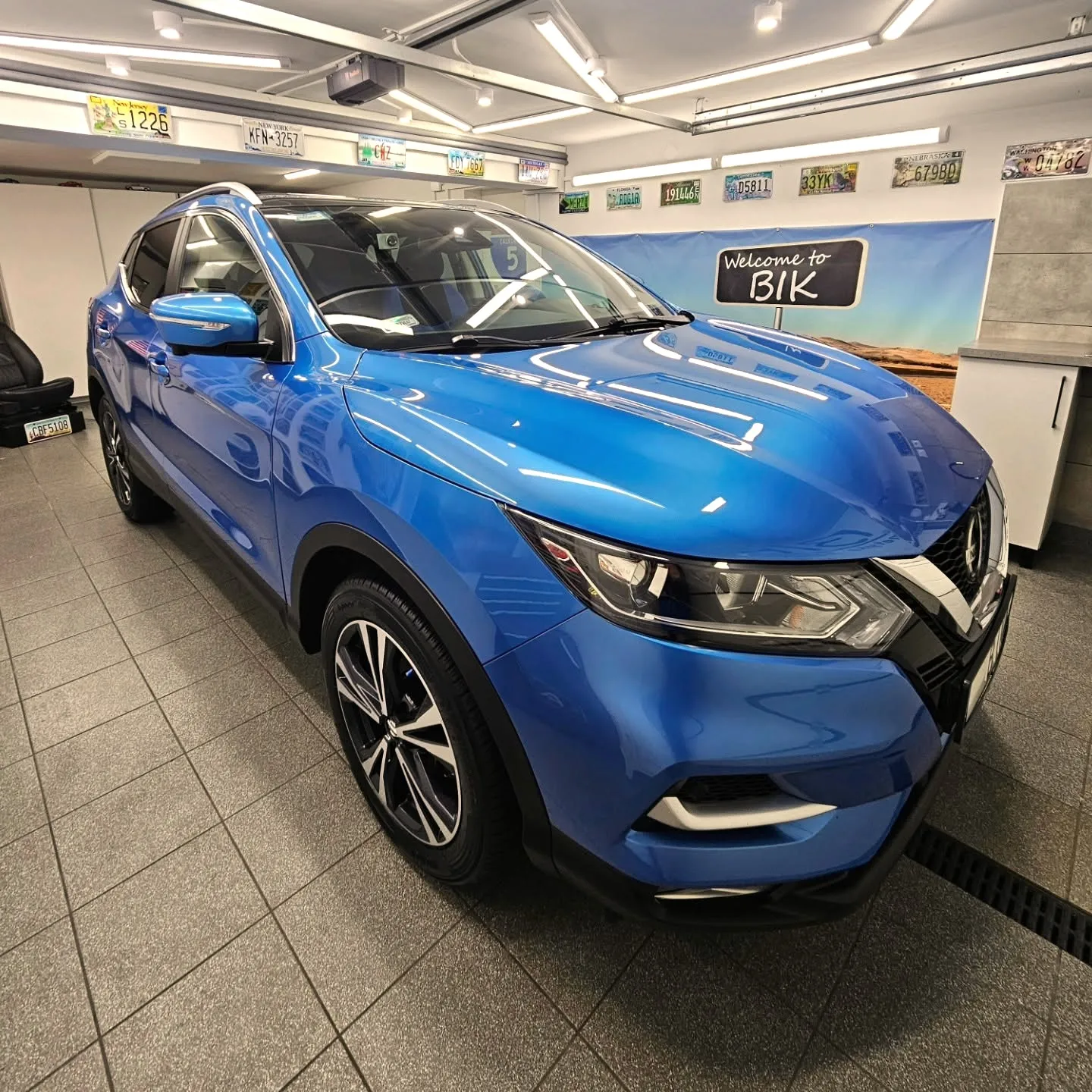 Niebieski Nissan Qashqai w studiu BIK z tablicą Welcome to BIK w tle