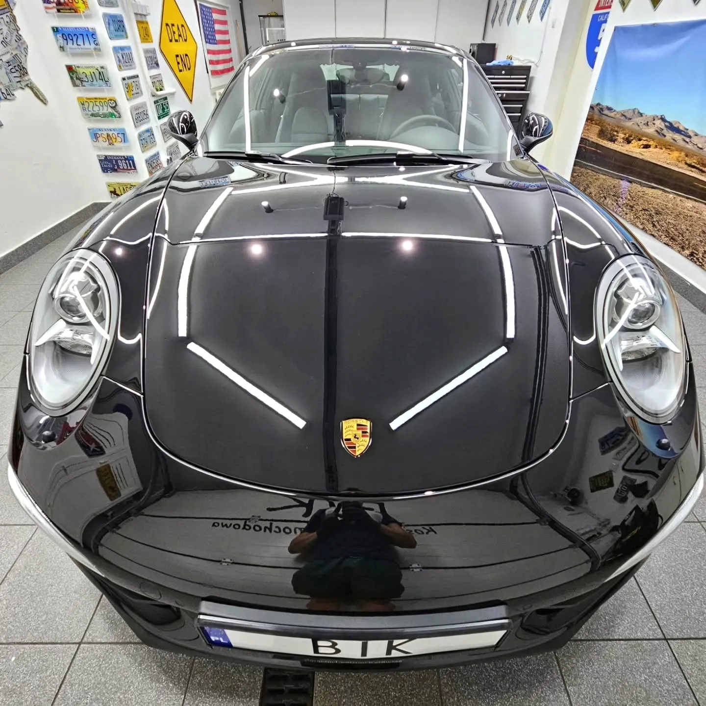 Maska czarnego Porsche 911 z ostrym odbiciem świateł po korekcie lakieru